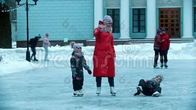 一位年轻的母亲穿着红色<strong>羽绒服</strong>和她的孩子们在冰上滑冰